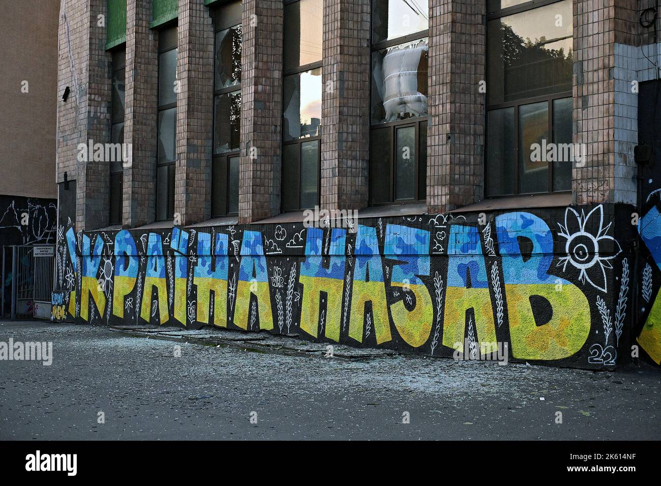 ZAPORIZHZHZHIA, UCRAINA - 10 OTTOBRE 2022 - vetro frantumato dall'ondata di esplosione nell'edificio con un graffito patriottico, Zaporizhzhzhia, Ucraina sudorientale. Credit: Ukrinform/Alamy Live News Foto Stock