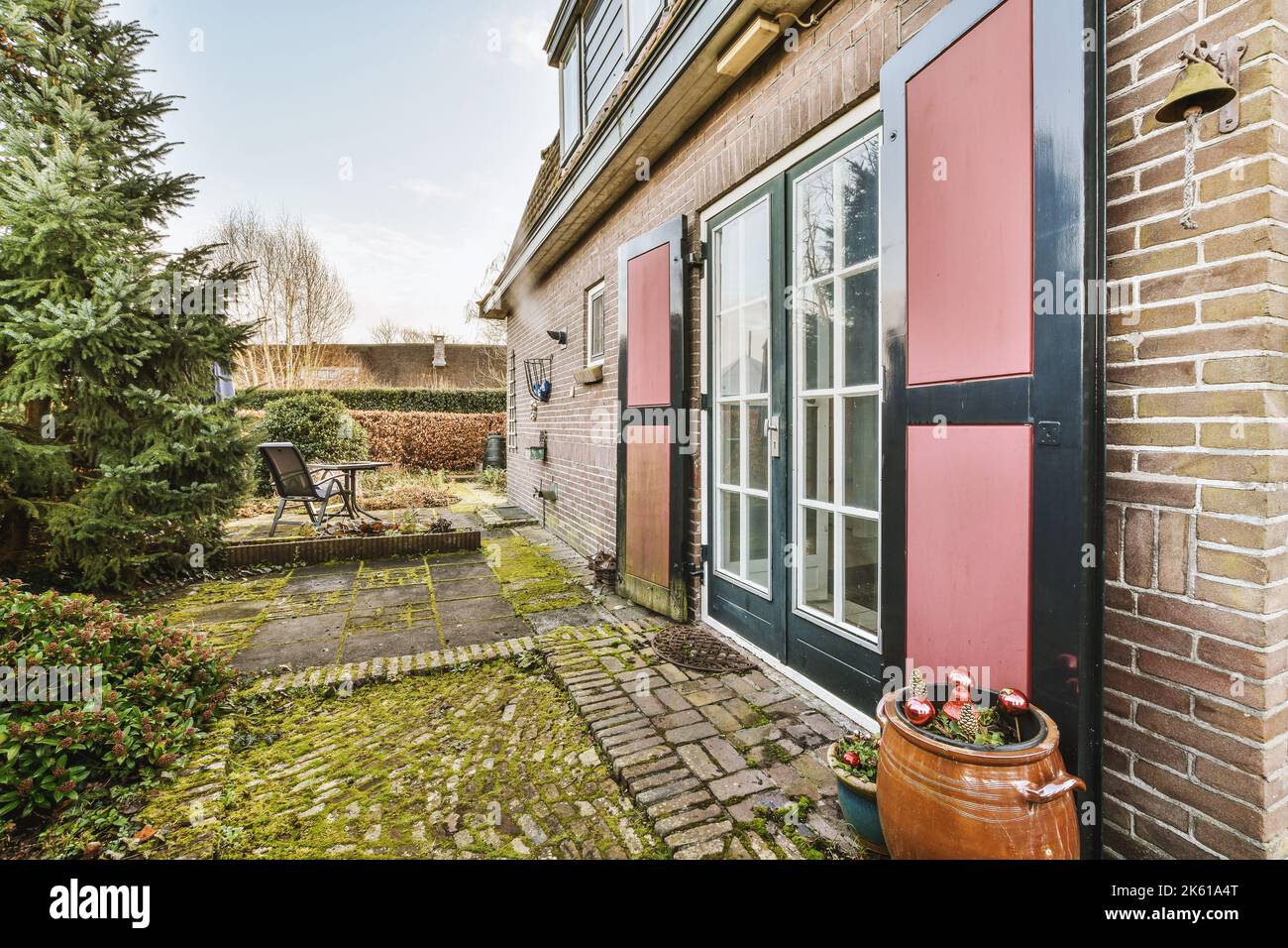 Pulito patio pavimentato con piccolo giardino e casa in mattoni Foto Stock