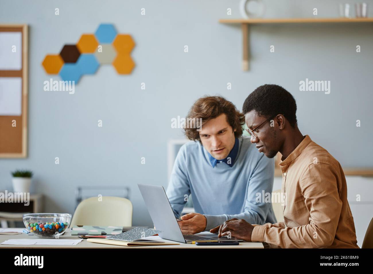 Immagine laterale di due sviluppatori di software che utilizzano il laptop insieme mentre lavorano al progetto nell'ufficio dell'AZIENDA IT, spazio copia Foto Stock