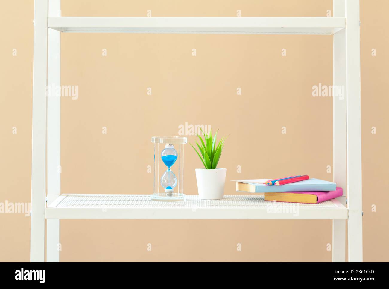 Scaffale bianco con libri e cancelleria contro il muro beige Foto Stock