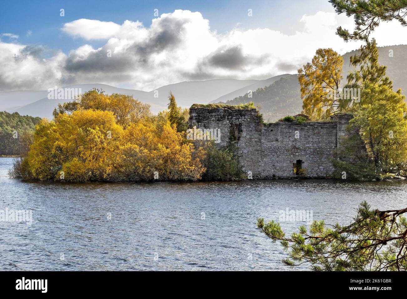 Loch an Eilein Aviemore Scozia alberi con fogliame autunnale circondano il castello su un'isola le montagne Cairngorm in lontananza Foto Stock