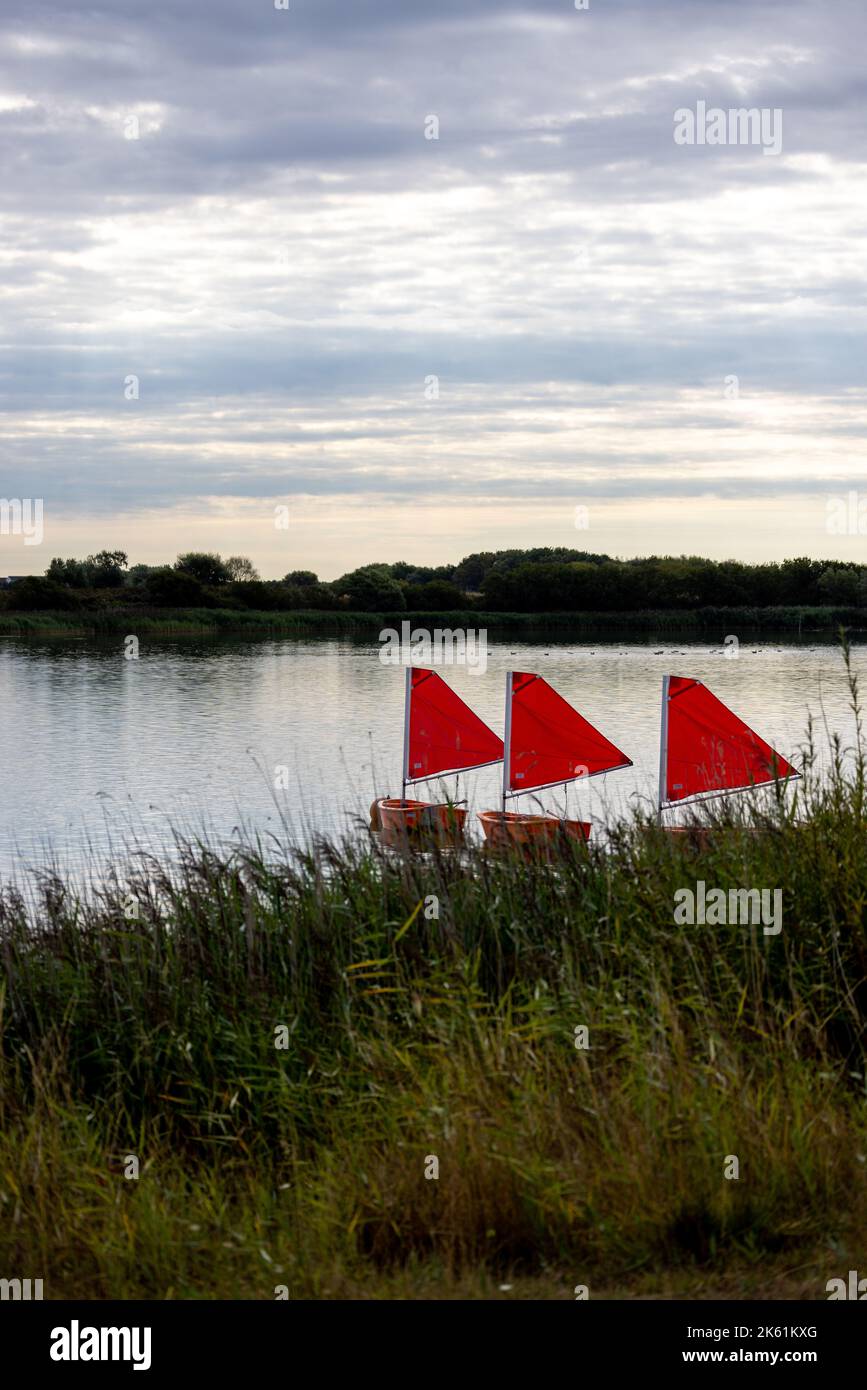 Piccole barche con vele rosse su un lago Foto Stock