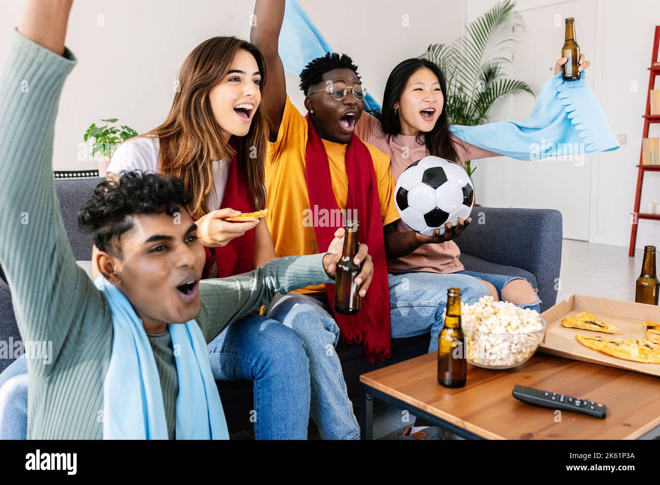 Diversi giovani tifosi amici che guardano il calcio in televisione a casa Foto Stock