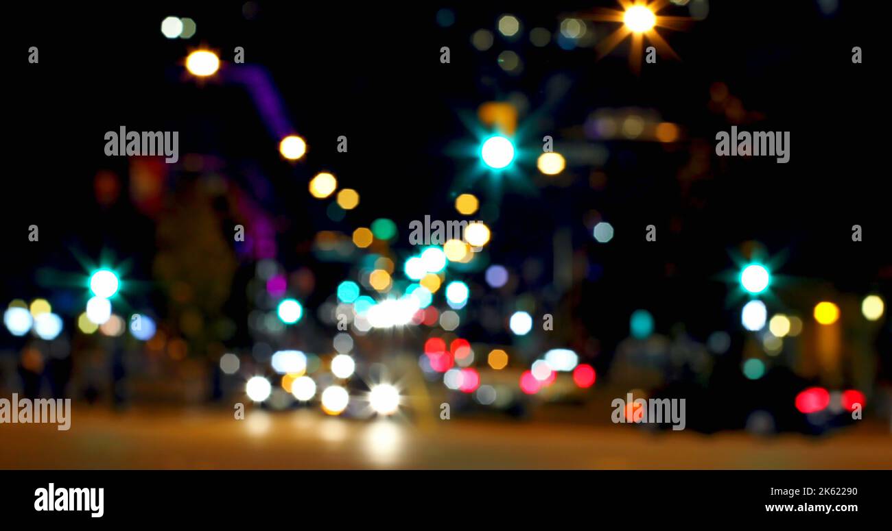 Foto a tutto campo di una strada sfocata con luci di strada multicolore illuminate di notte in città Foto Stock