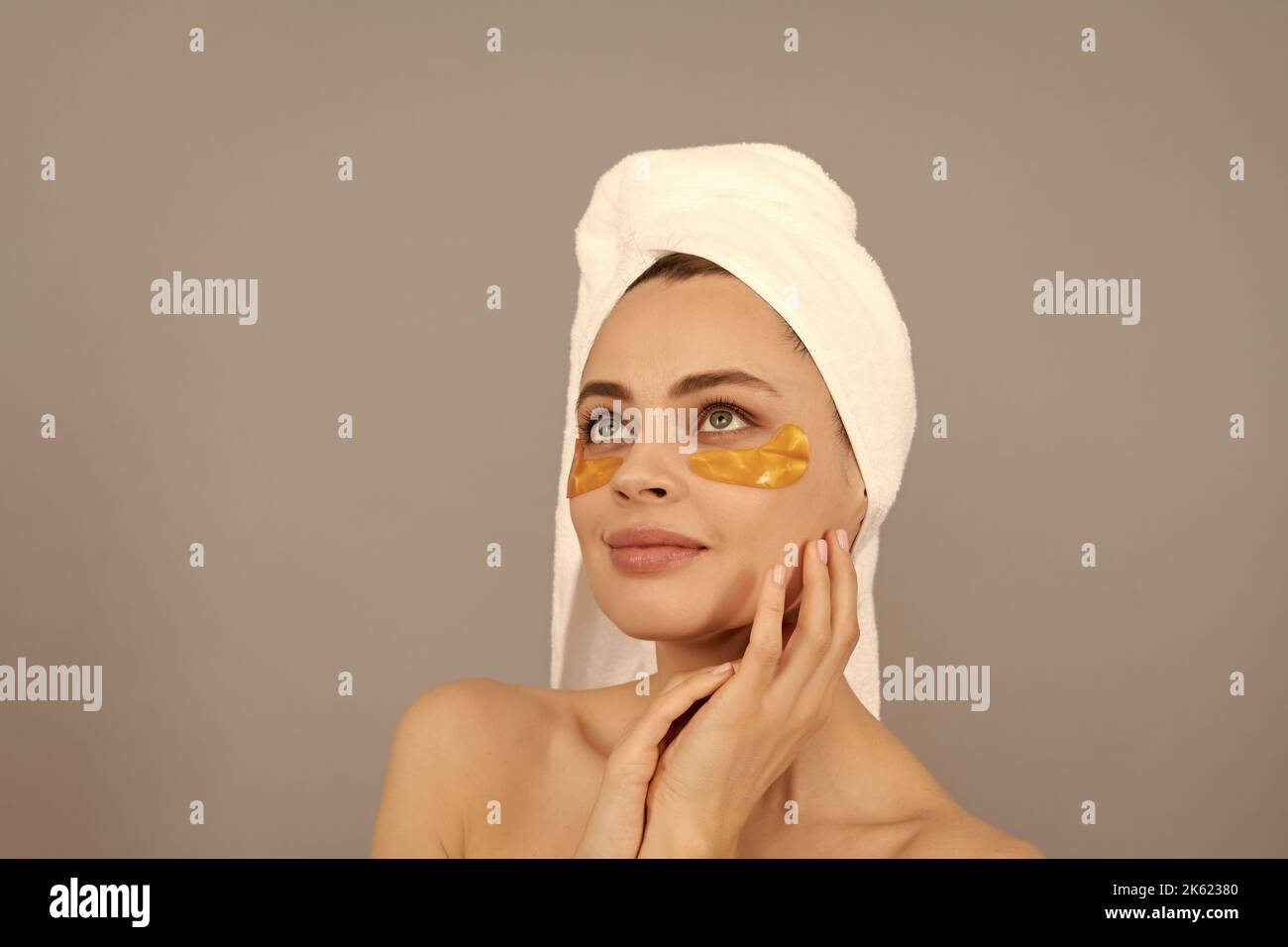Get Your Skin gorgeous. Cosmetology. Giovane donna in spugna asciugamano usare patch. Giorno di bellezza. Foto Stock