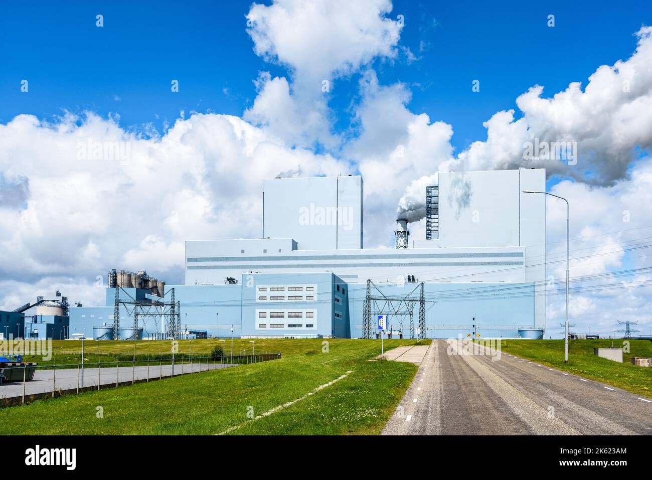 Vista di una centrale a carbone in una giornata estiva di sole. I nastri di fumo bianchi densi formano un camino. Foto Stock