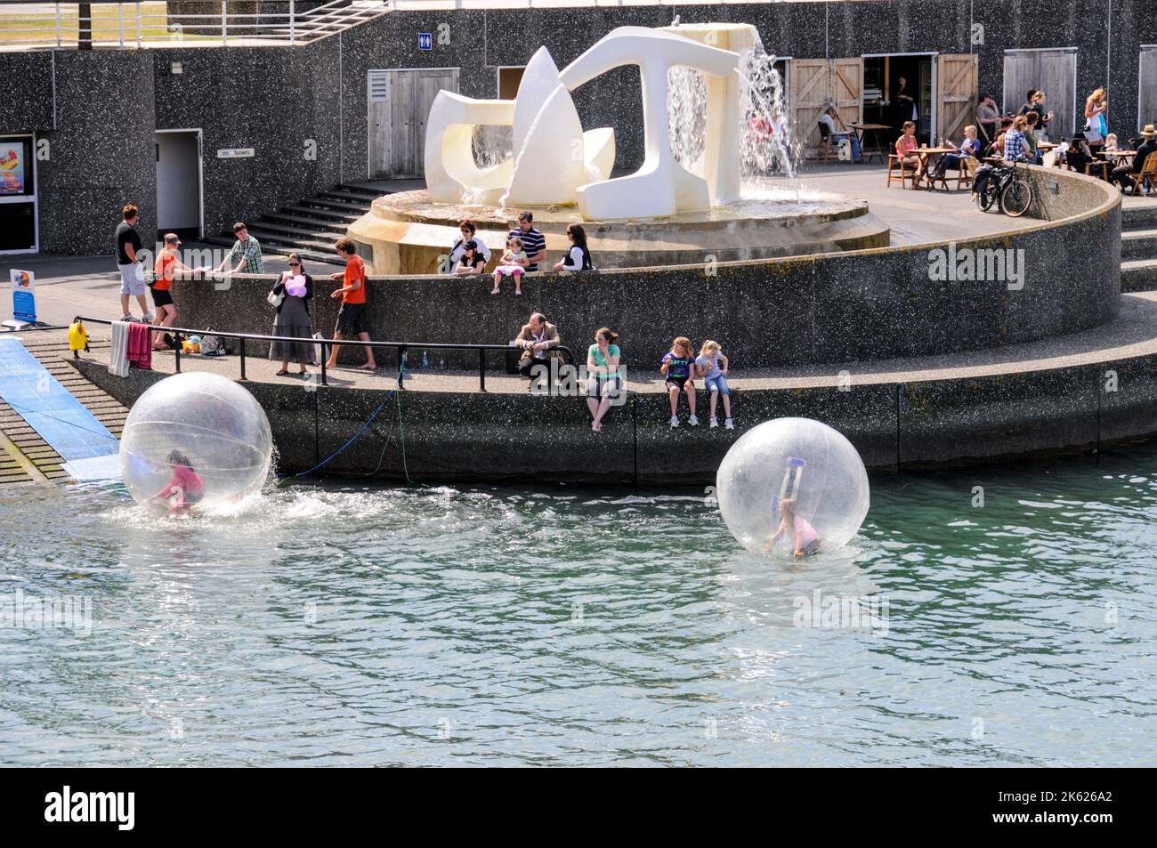 I bambini si divertono all'interno di una bolla d'acqua a piedi sulla Laguna Whairepo nel quartiere di Wellington sul lungomare di Wellington, sull'isola nord di New Ze Foto Stock