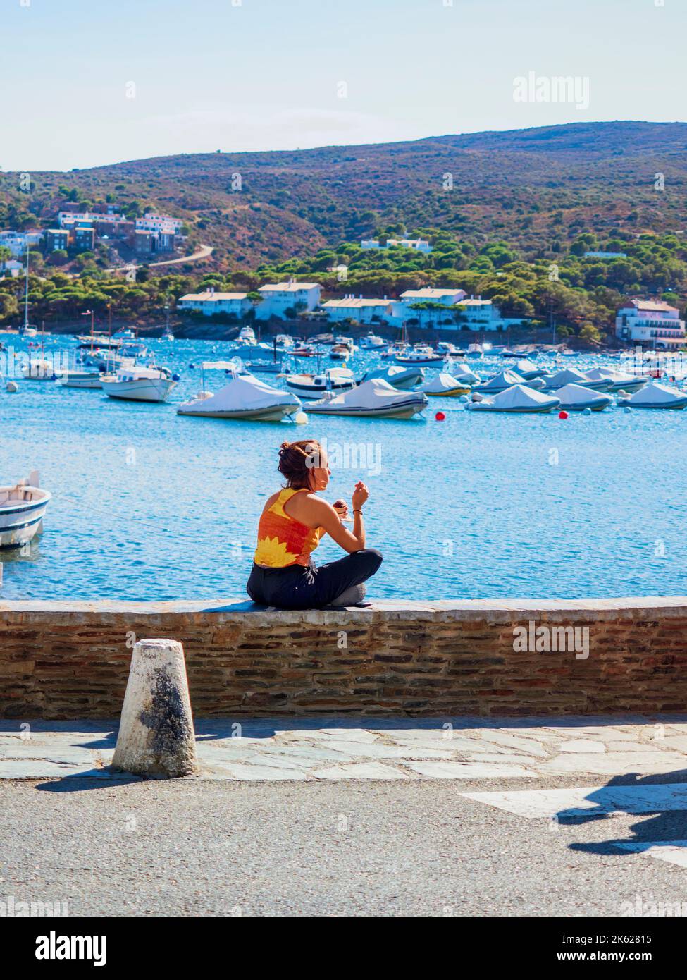 Una giovane ragazza turistica che guarda il paesaggio costiero della città di Cadaqués, Girona, Spagna. Foto Stock