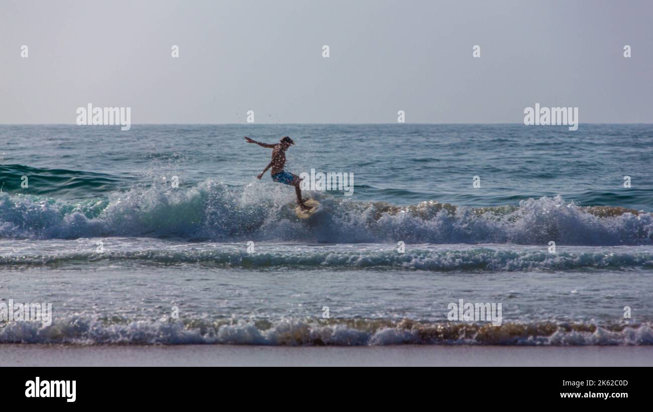 Un uomo sta navigando su una tavola da surf nella spiaggia di Agadir Foto Stock