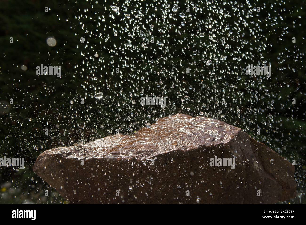 Gocce di pioggia che cadono su una roccia Foto Stock