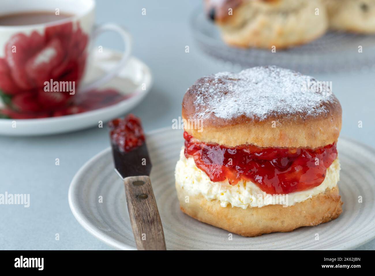 Un fresco e tradizionale scone inglese fatto in casa. La torta è spaccata e ripiena di marmellata e ricoperta con panna grumata densa. Un delizioso tè alla crema Devon. Foto Stock