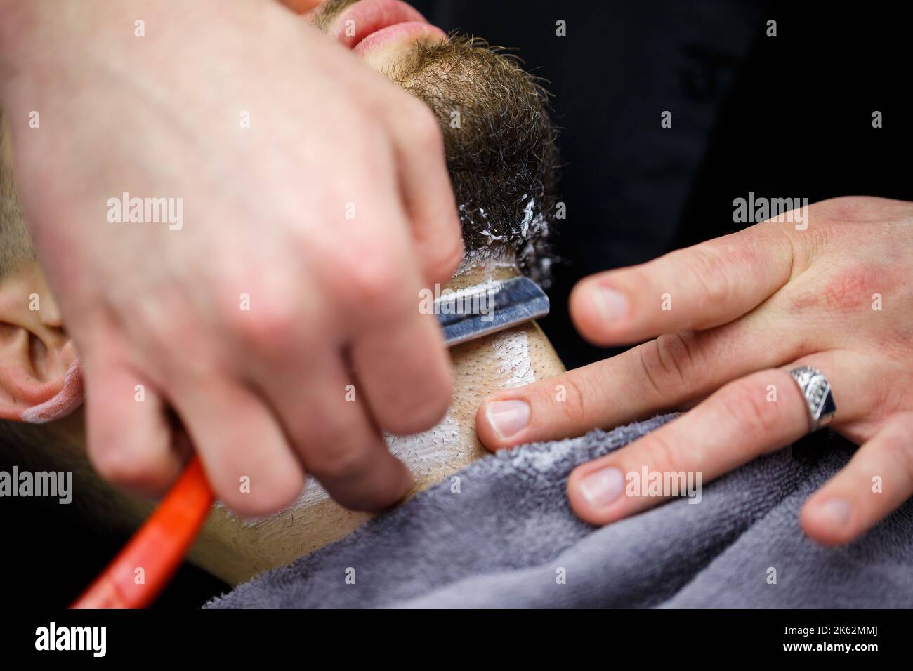 Inimicchiando una barba in un salone del barbiere ad un uomo Foto Stock