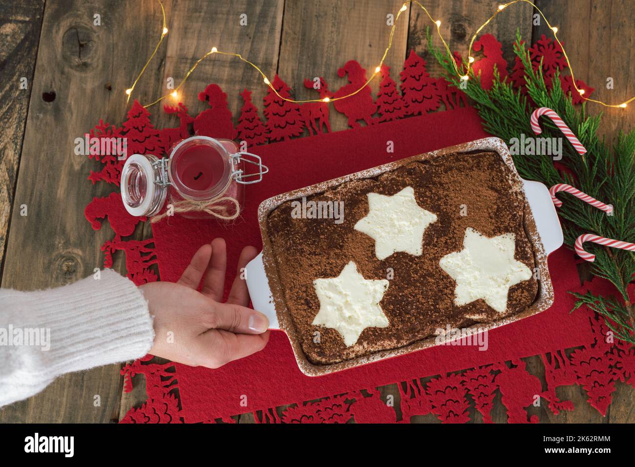 Dessert tradizionale italiano. Tiramisù decorato con stelle e mano che regge il vassoio decorazione di Natale. Spazio di copia. Vista dall'alto. Foto Stock