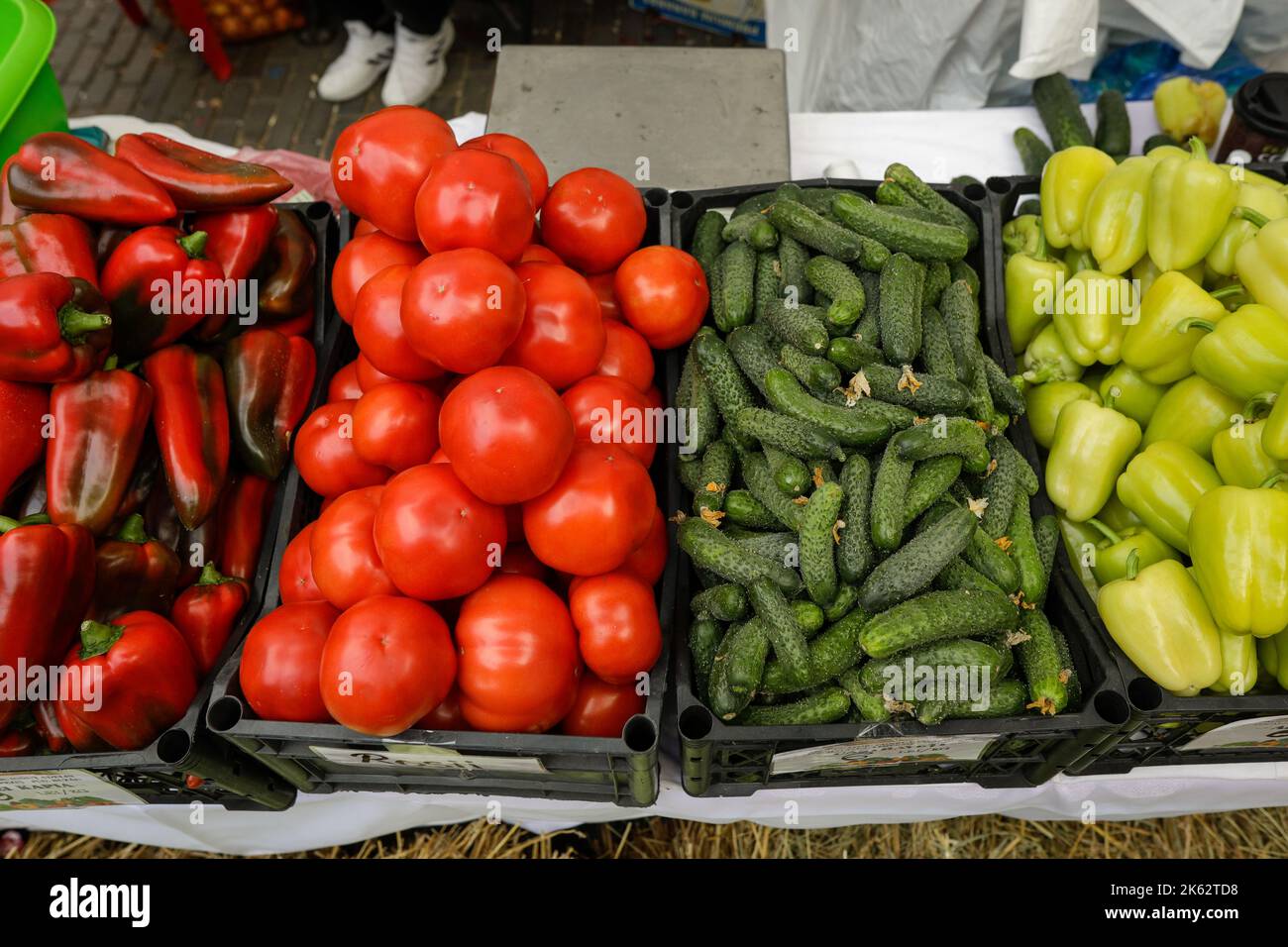 Profondità di campo ridotta (fuoco selettivo) dettagli con peperoni rossi e verdi, pomodori e cetrioli in un mercato agricolo europeo. Foto Stock