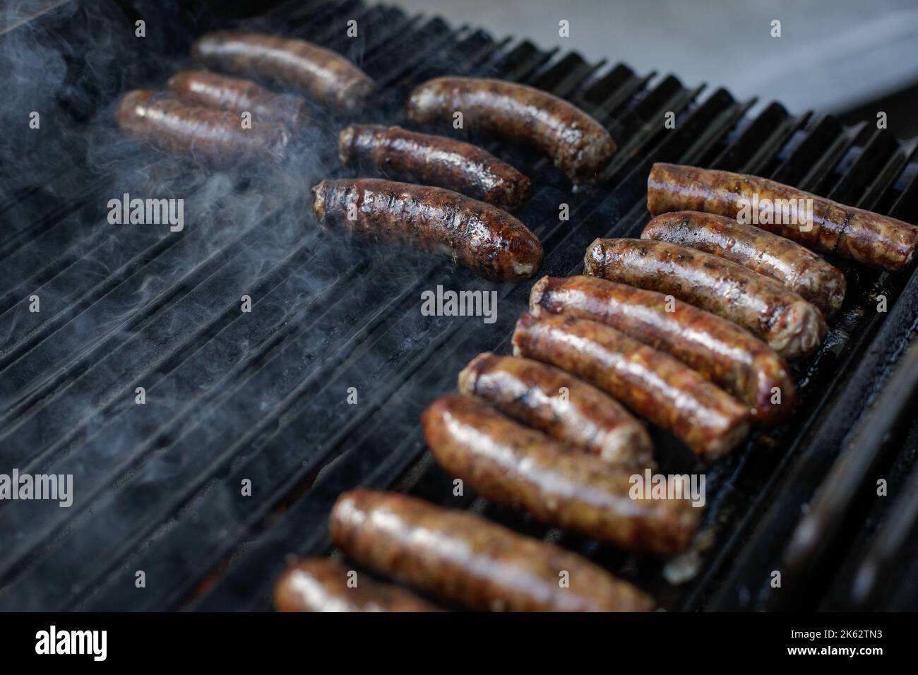 Profondità di campo poco profonda (focus selettivo) dettagli con salsicce di maiale cucina su una griglia barbecue, in un mercato agricolo europeo. Foto Stock