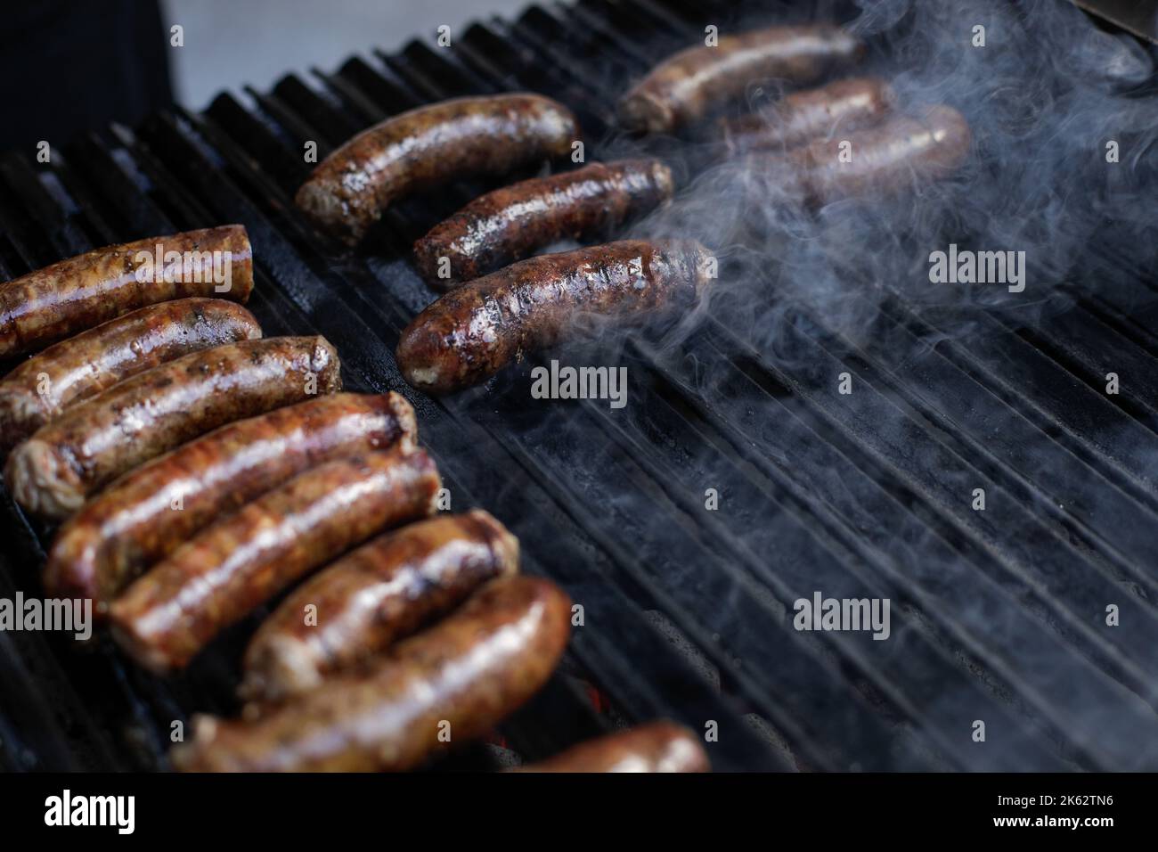 Profondità di campo poco profonda (focus selettivo) dettagli con salsicce di maiale cucina su una griglia barbecue, in un mercato agricolo europeo. Foto Stock