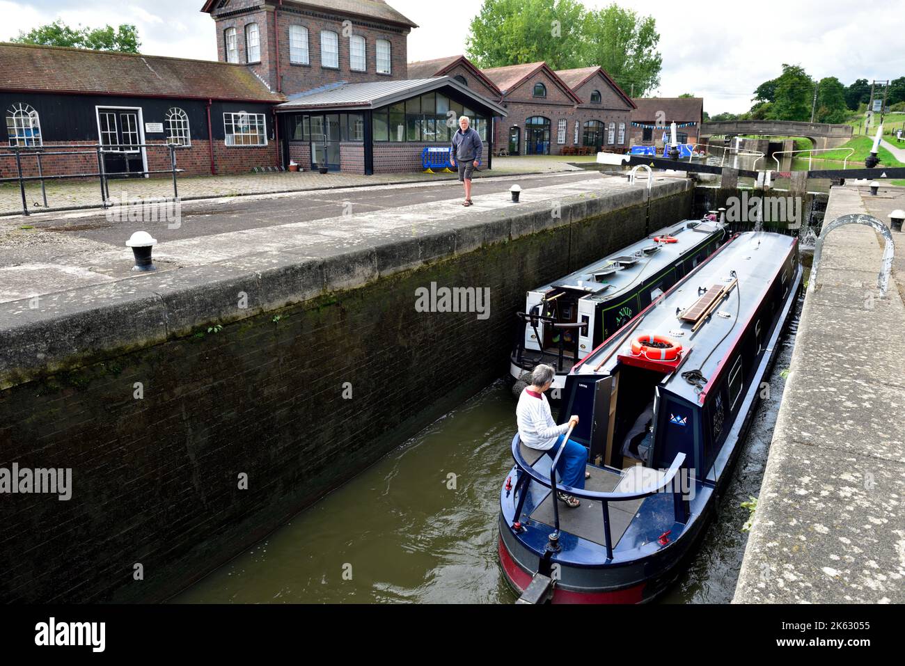 Due barche strette sui canali che attraversano i cancelli di chiusura durante il volo di 21 chiuse a Hatton Locks sul Canal Grand Union, Warwick, Warwickshire Foto Stock