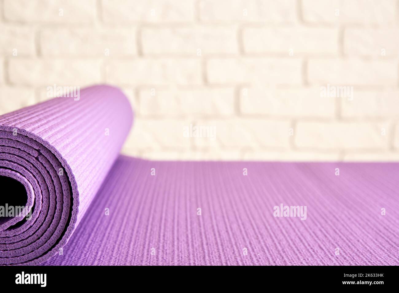 Sottile tappeto viola yoga sul pavimento in legno nella moderna palestra. Accessori per allenamento e aerobica Foto Stock