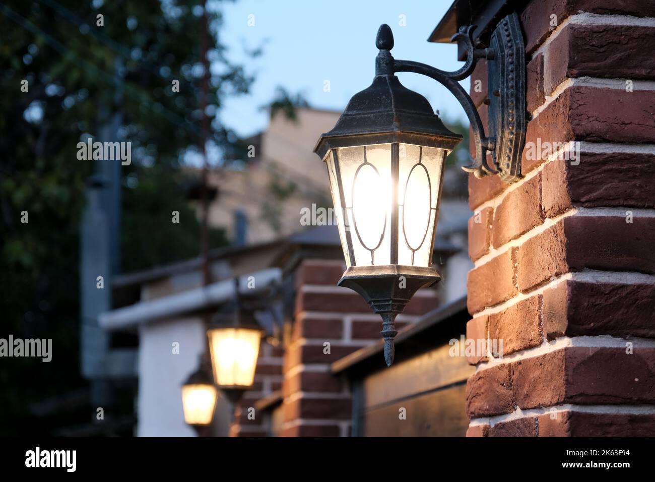 La strada scura è illuminata da lampioni stradali. Lanterna vintage su un muro di mattoni la sera Foto Stock