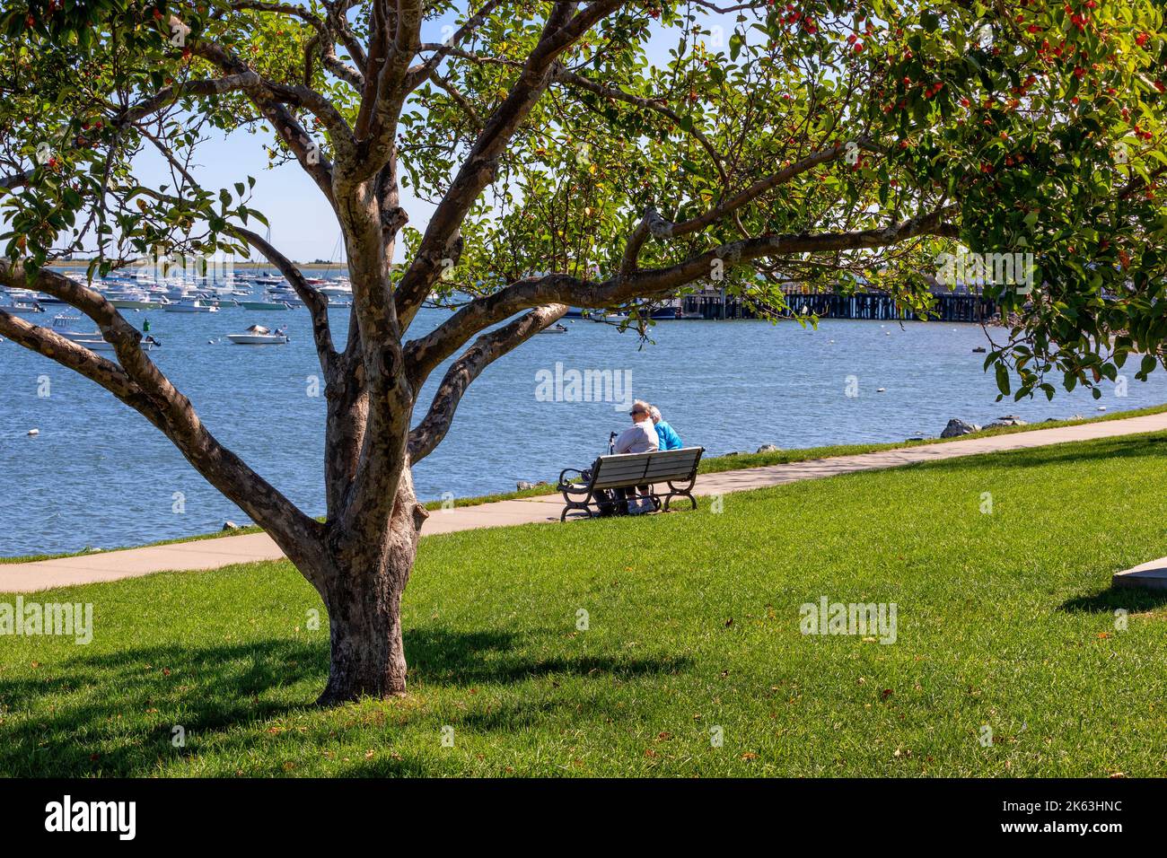 Plymouth, Massachusetts, USA - 15 settembre 2022: Due persone si siedono su una panchina ammirando la vista del porto in un giorno di sole autunno. Foto Stock