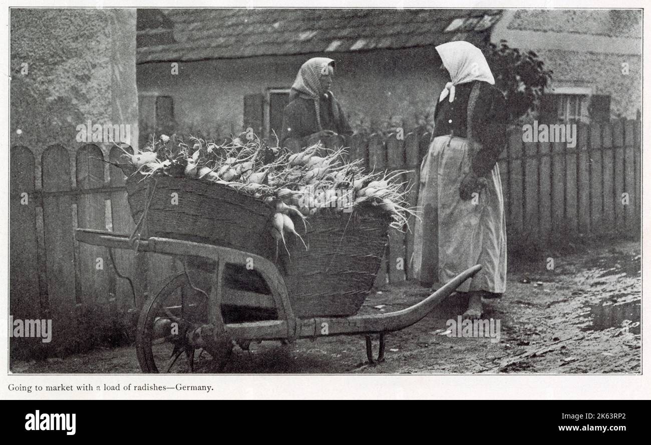 Due donne a piedi scalzi che vanno al mercato con un barile di aromi appena raccolti. Foto Stock