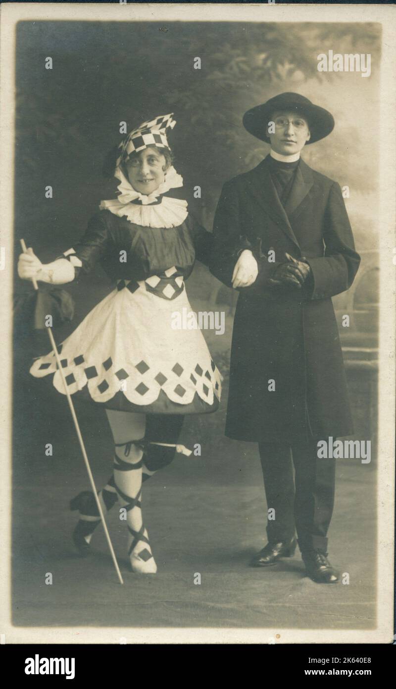 Due persone in abiti eleganti. La ragazza a sinistra indossa un fantastico abito tipo Pierrot che ricorda Paul Poiret, o almeno gli abiti più sgargianti della prima guerra mondiale, mentre al contrario, la sua amica è vestita da vicario. Foto Stock