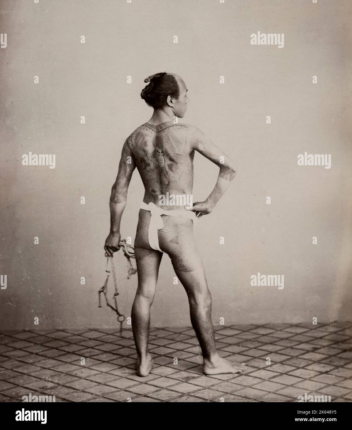 Fotografia d'annata del XIX secolo - sposo tatuato in un panno, tenendo una briglia, mostrando i tatuaggi sulla schiena, Giappone, circa 1880 Foto Stock