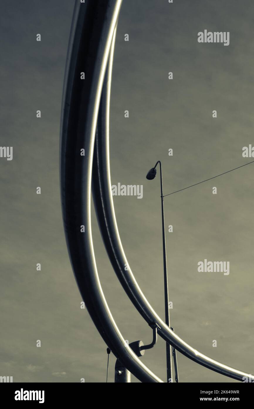Una scala di grigi verticale di tubi semicircolari che si diffondono attraverso la cornice e una torcia elettrica sullo sfondo Foto Stock