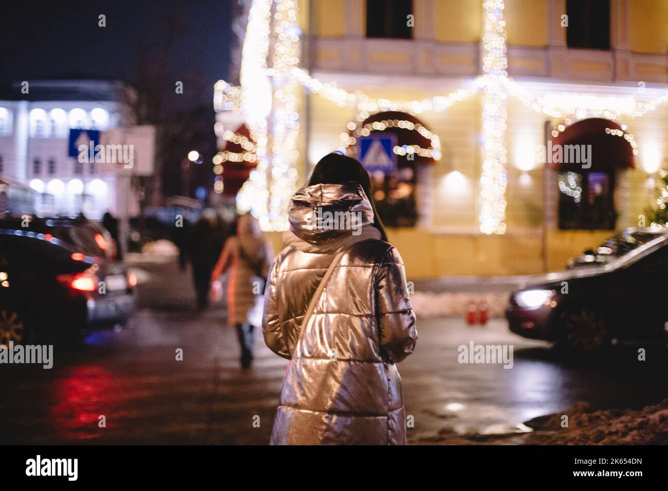 Vista posteriore della donna che cammina in città di notte in inverno Foto Stock