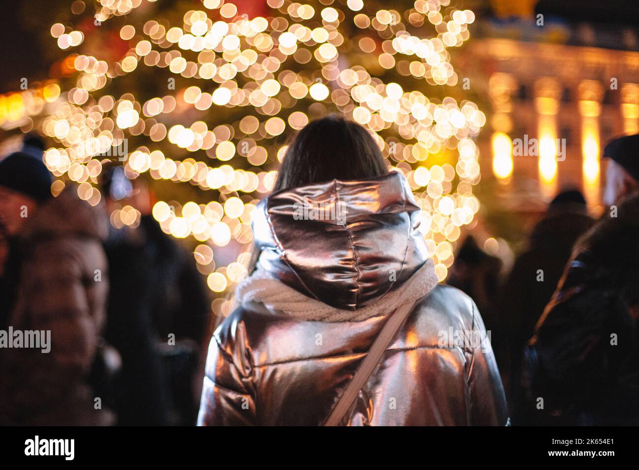 Vista posteriore della donna che guarda l'albero di Natale in piedi in città di notte Foto Stock