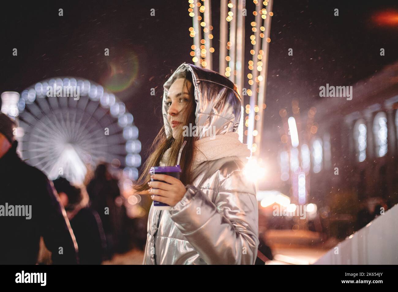 Giovane donna in piedi nel mercato di Natale in città di notte Foto Stock