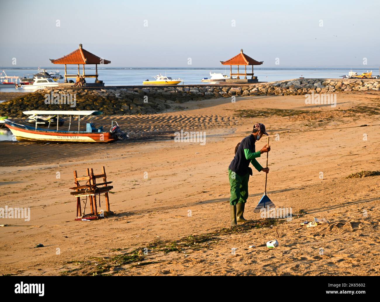 Bali, Indonesia - 12 settembre 2022; l'uomo spazzando la lettiera e rifiuti dalla spiaggia in mattina presto, Sanur, Bali, Indonesia Foto Stock
