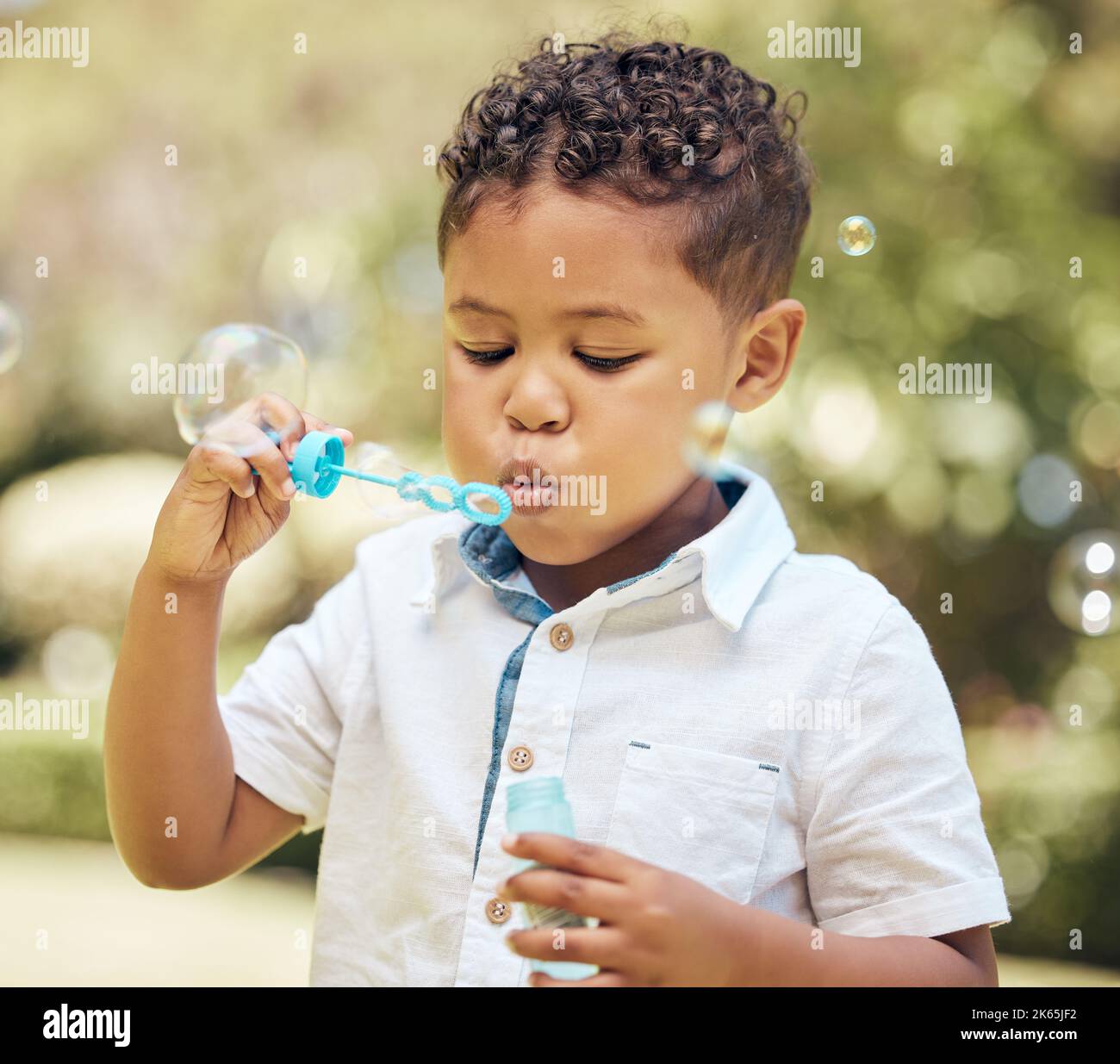 Theres nessun altro posto Id piuttosto essere. Un bambino piccolo che soffia le bolle in un giardino a casa. Foto Stock