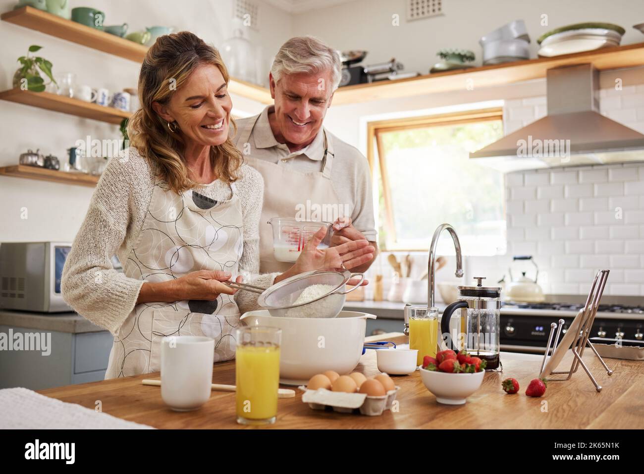 Anziani, coppie e in cucina mentre cucinano, cuocendo e felici insieme in un momento divertente. Uomo anziano, donna e il sorriso di pensione in casa, legame e. Foto Stock