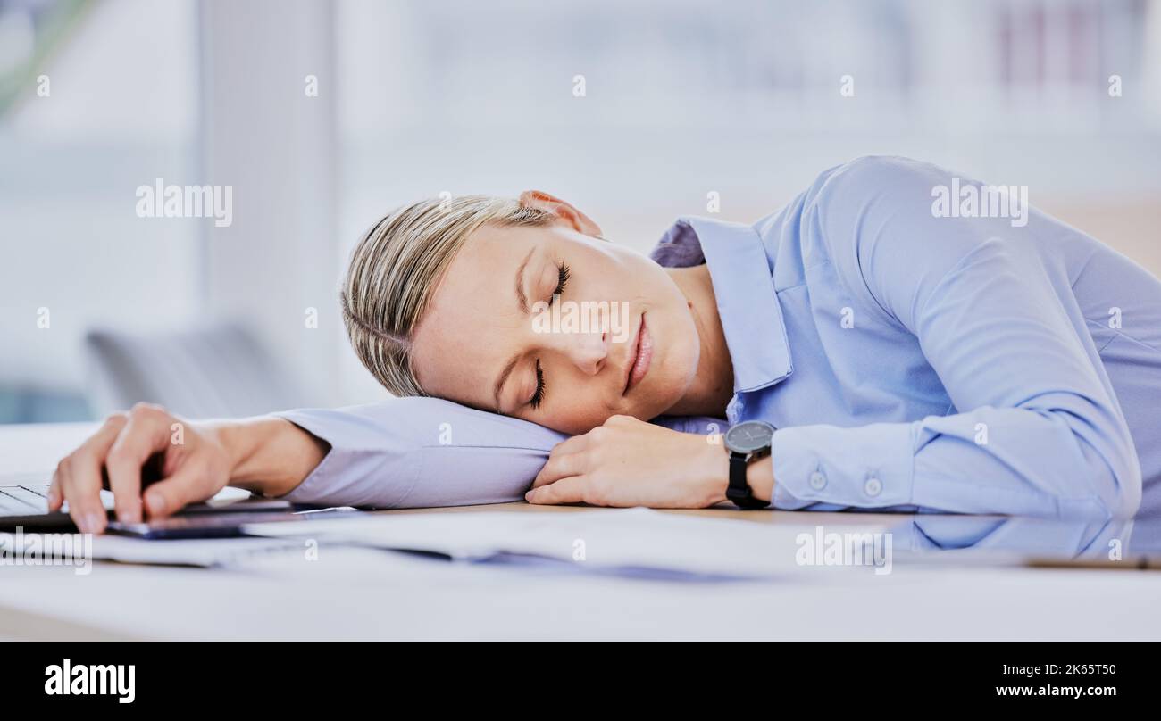 Giovane donna d'affari caucasica stanca seduta alla scrivania e addormentata. Esausta giovane professionista donna che prende un pisolino sdraiato la testa sul tavolo Foto Stock