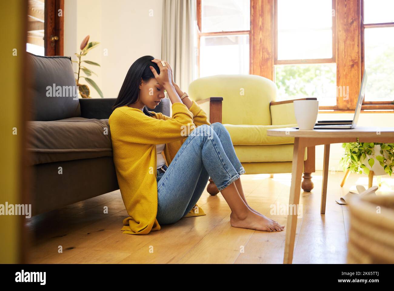 Donna stressata, depressione e solitaria nel soggiorno seduto sul pavimento a casa. Giovane donna triste che soffre di problemi di salute mentale e. Foto Stock
