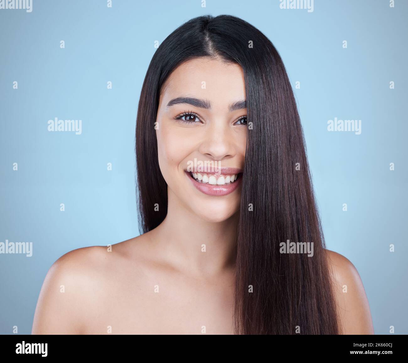 La parte più tagliata del mazzo. Studio ritratto di una bella giovane donna che mostra i suoi lunghi capelli setosi su uno sfondo blu. Foto Stock