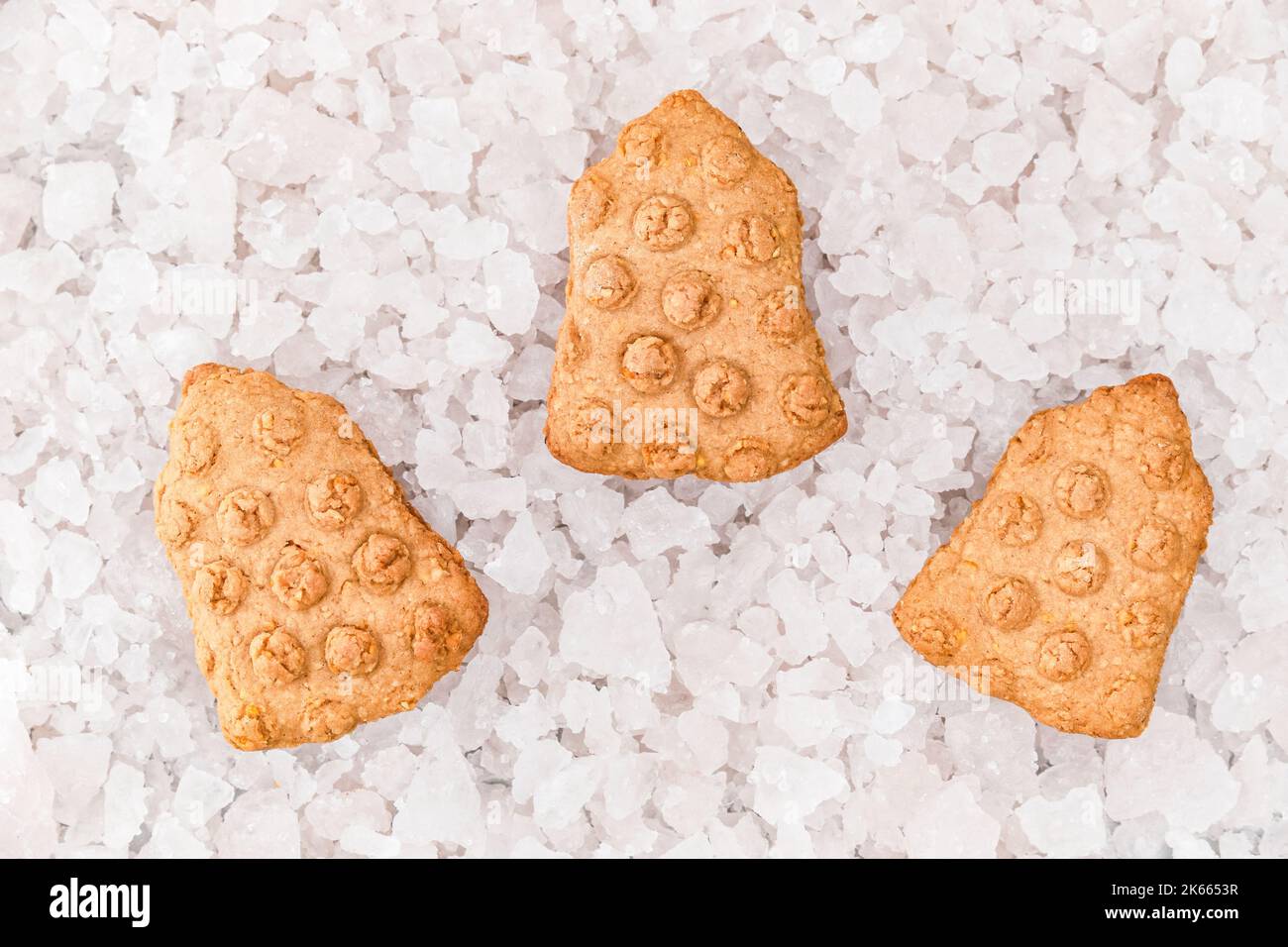 Vista dall'alto dei biscotti a forma di campane di Natale sullo sfondo di pezzi decorativi di ghiaccio. Foto Stock