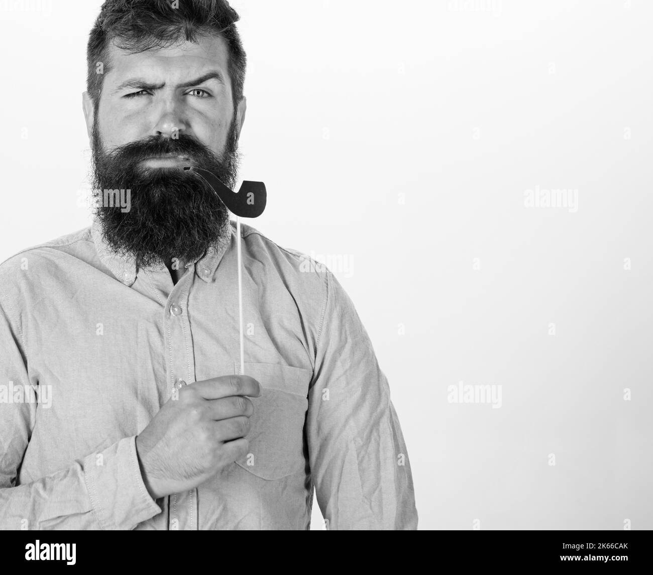 Il ragazzo fuma il tubo del tabacco. Hippster con barba e baffi sul viso serio posa con stand foto, spazio copia. Vecchio concetto di abitudini. Uomo che tiene Foto Stock