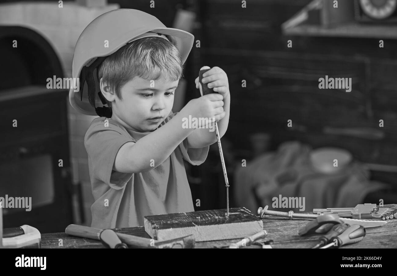 Bambini imparano a usare il cacciavite. Bambino concentrato in casco arancione lavorando in officina. Concetto di occupazione futura Foto Stock