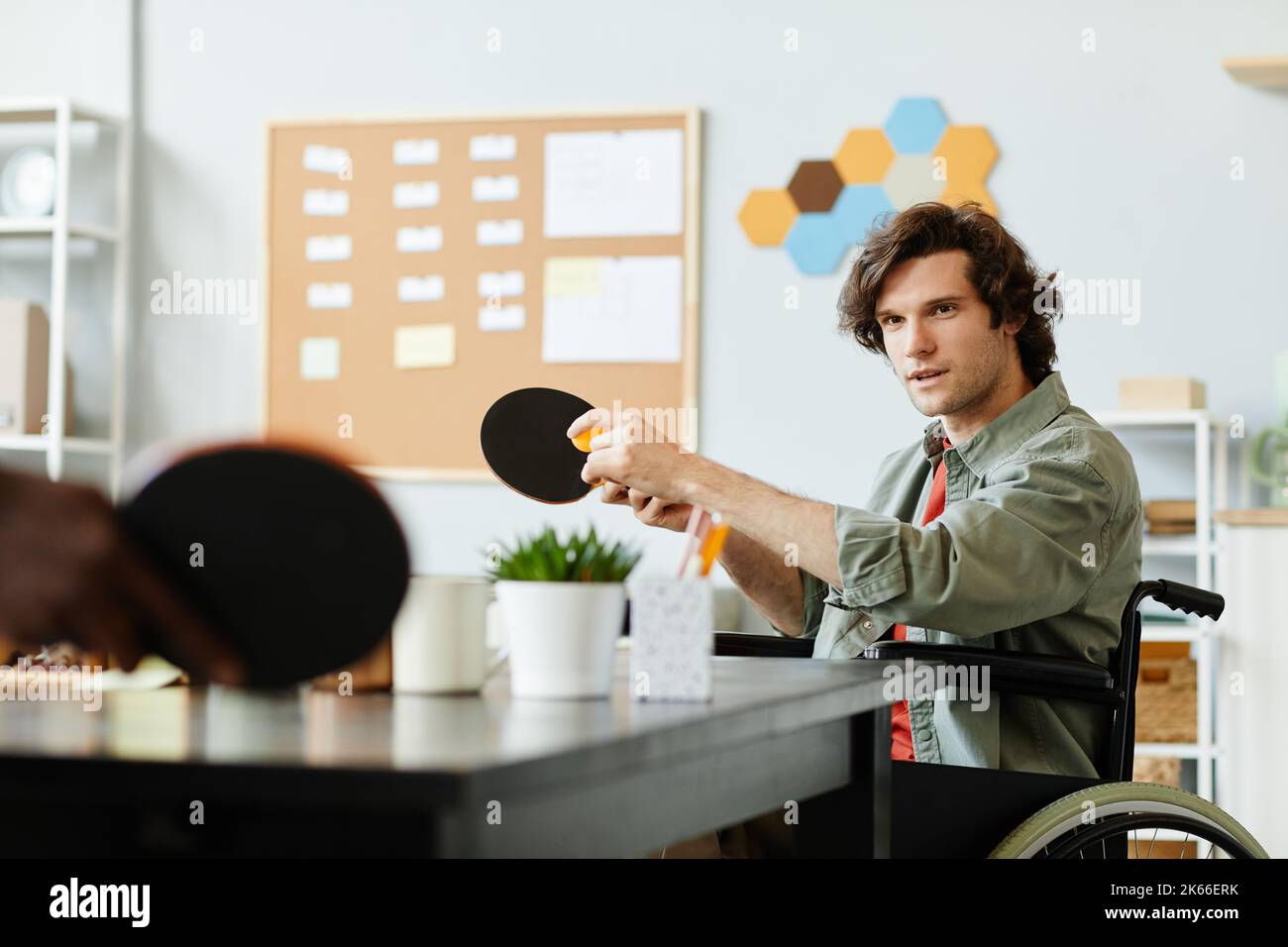 Ritratto di giovane caucasico con disabilità giocando a ping pong in ufficio sala pausa, spazio copia Foto Stock