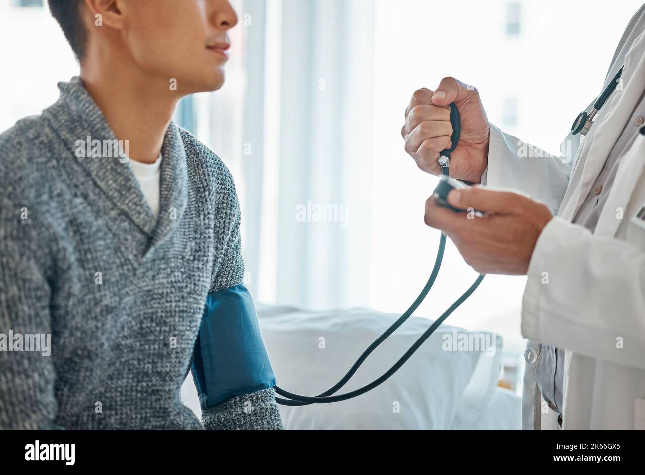 Primo piano di un medico caucasico in uniforme bianca che parla con un paziente di sesso maschile in clinica privata mentre si usa uno stetoscopio. GP maschio o terapista consultare l'uomo Foto Stock