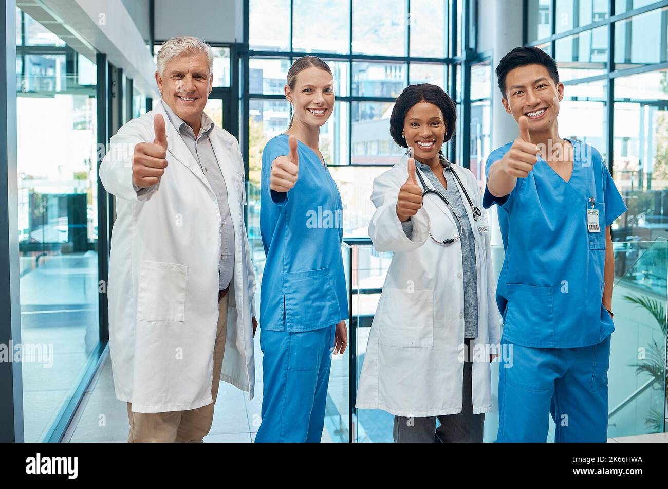 Un gruppo di medici che mostra un pollice in un ospedale moderno. Foto Stock