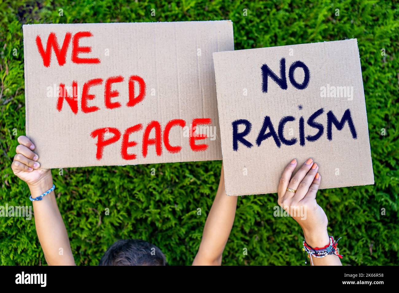 le mani dei giovani che tengono segni di cartone con slogan contro il razzismo Foto Stock