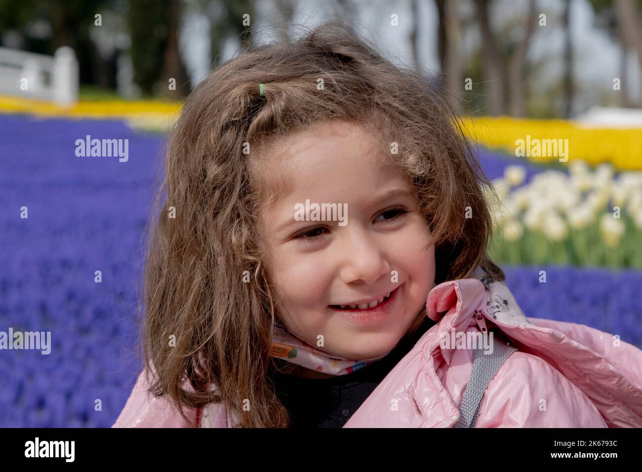 bambina sorridente nel parco decorata con tulipani colorati. Faccia selettiva delle ragazze di fuoco Foto Stock
