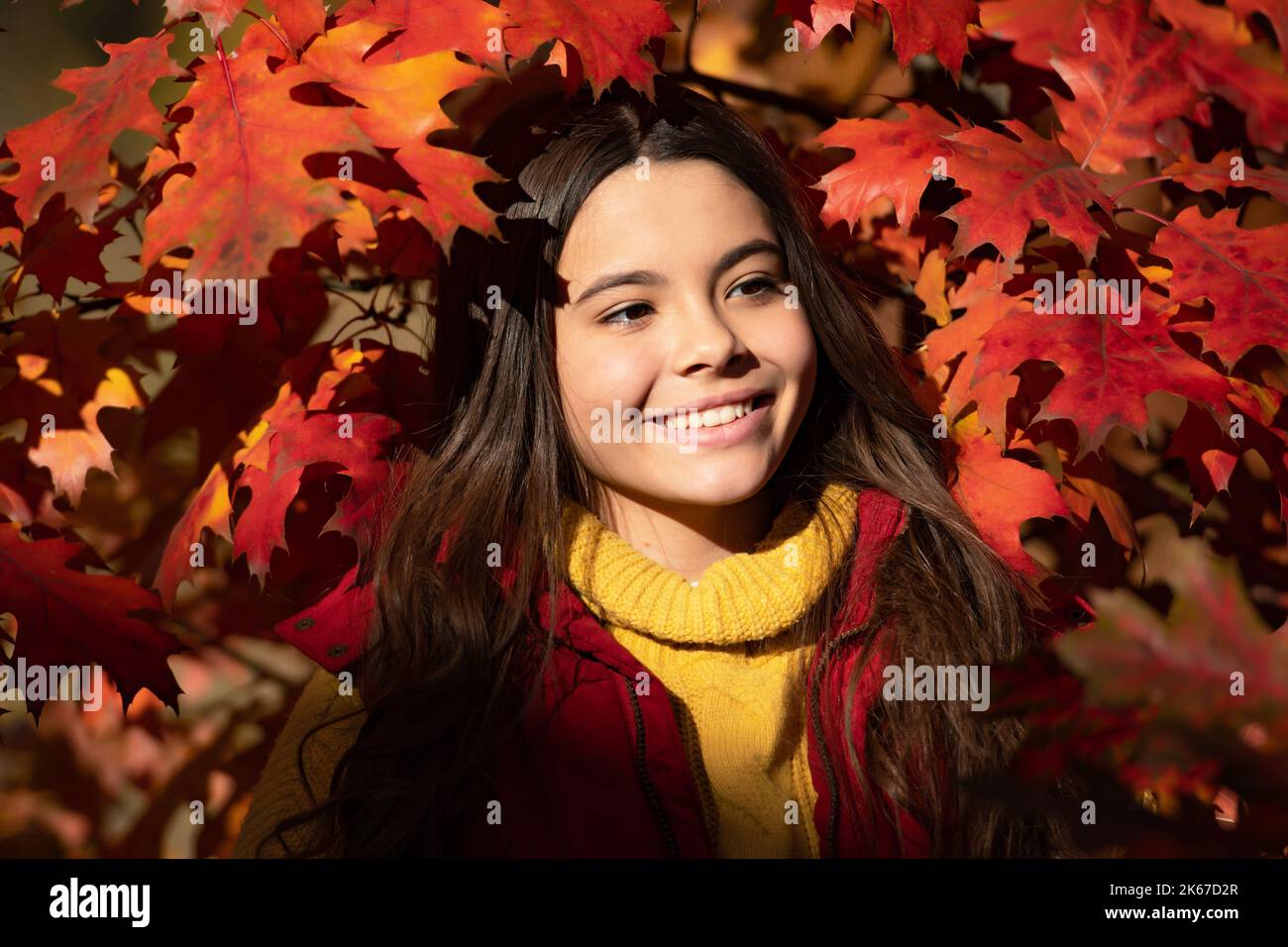 Autunno capretto ragazza faccia su sfondo foglia caduta. Autunno bambino adolescente ragazza 12, 13, 14 anni ritratto. Bambino allegro in piedi a bell'autunno Foto Stock