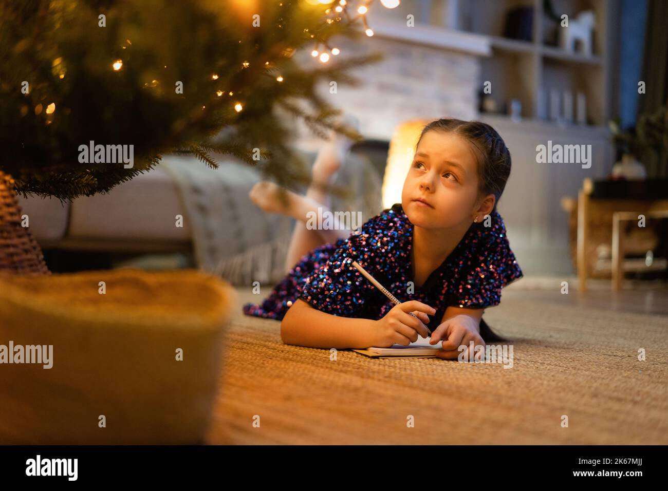 natale, vacanze e concetto di infanzia - ragazza sorridente facendo lista dei desideri o lettera a babbo natale a casa Foto Stock