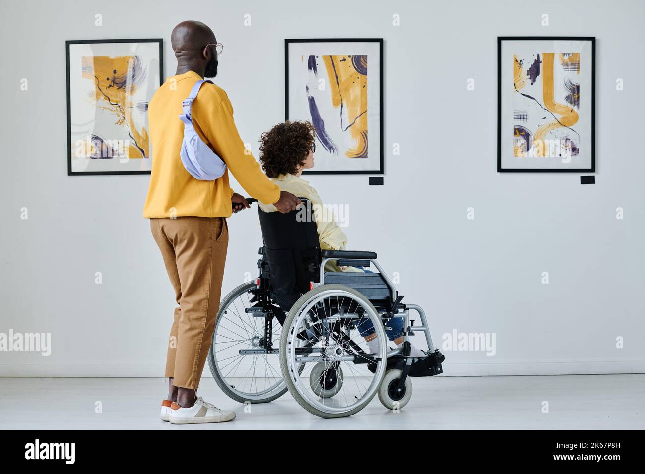 Giovane donna con disabilità che visita la galleria d'arte insieme al giovane Foto Stock