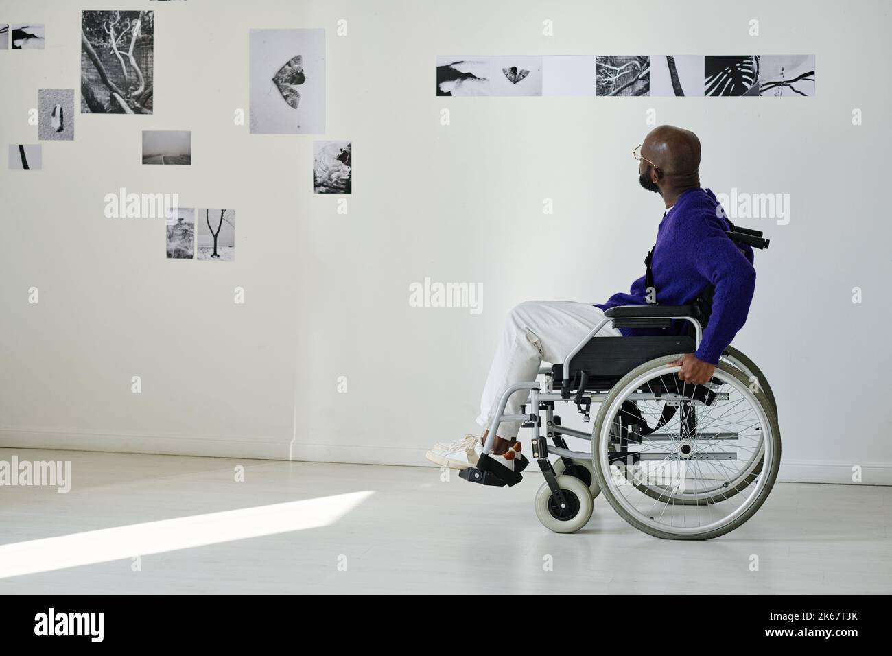 Uomo africano con disabilità visitando la galleria fotografica, egli gode di arte moderna Foto Stock