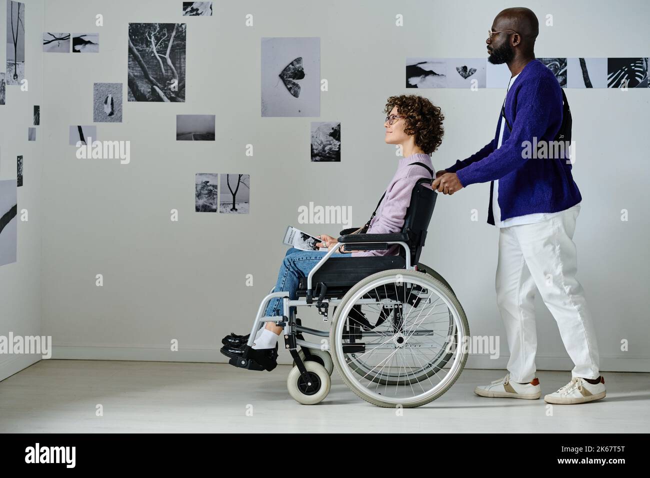 Coppia multietnica con disabilità visitando la galleria d'arte moderna Foto Stock